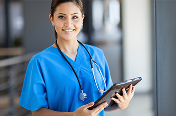Medical professional wearing blue scrubs and holding a clipboard